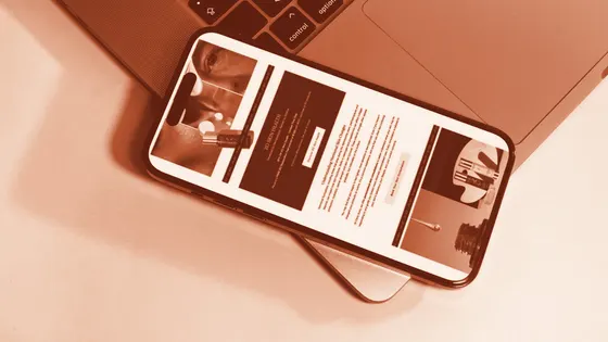 A phone showing an email design resting on a laptop