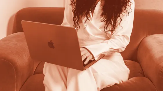 A woman working on a laptop in a velvet armchair