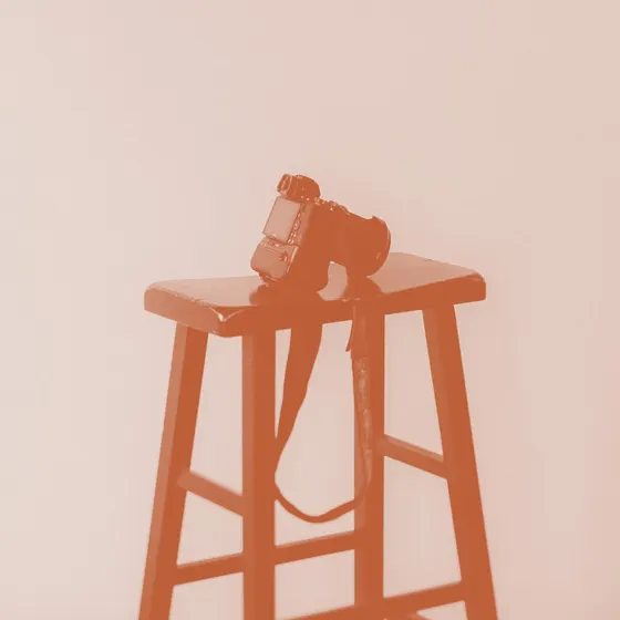 A camera resting on a wooden stool, toned in terracotta